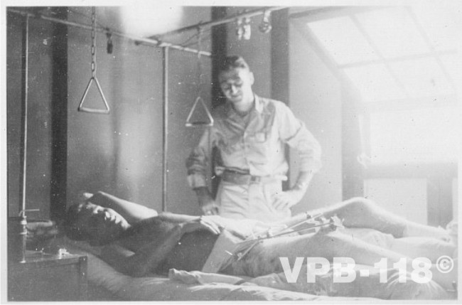 Ens. Sam Heublein visiting injuried airman in hospital in Guam, July 1945.